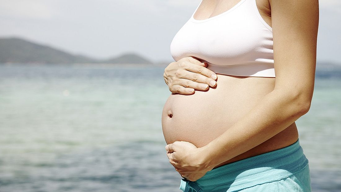 young pregnant woman doing yoga on a beach in thailand